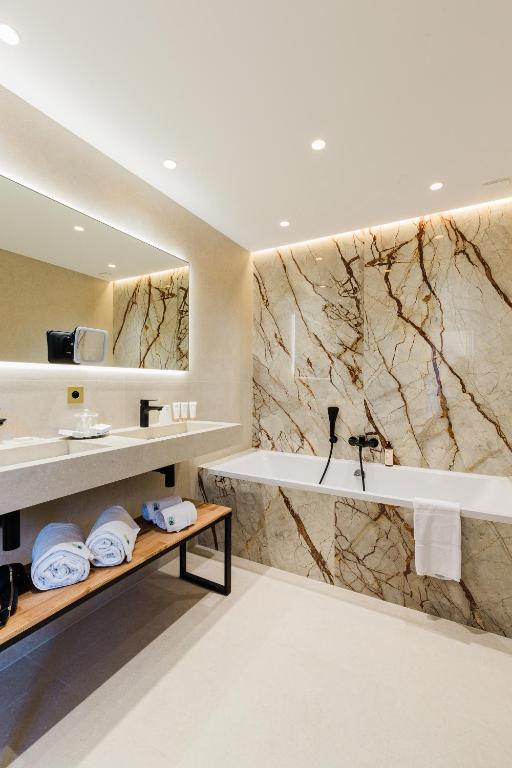 a bathroom with a tub and a sink at Hôtel Hélios in Juan-les-Pins