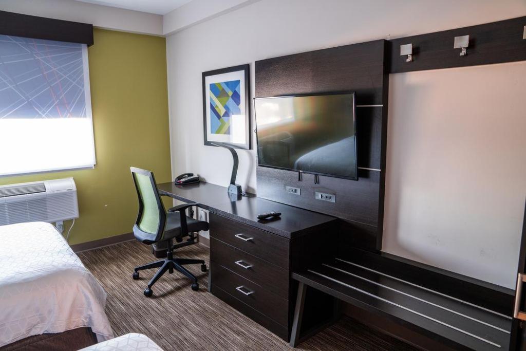 a hotel room with a desk with a tv and a bed at Holiday Inn Express Maspeth by IHG in Queens