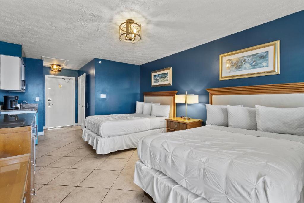 two beds in a hotel room with blue walls at Ocean View Hotel Room with Balcony- 2 Full Beds #22 in Fort Pierce