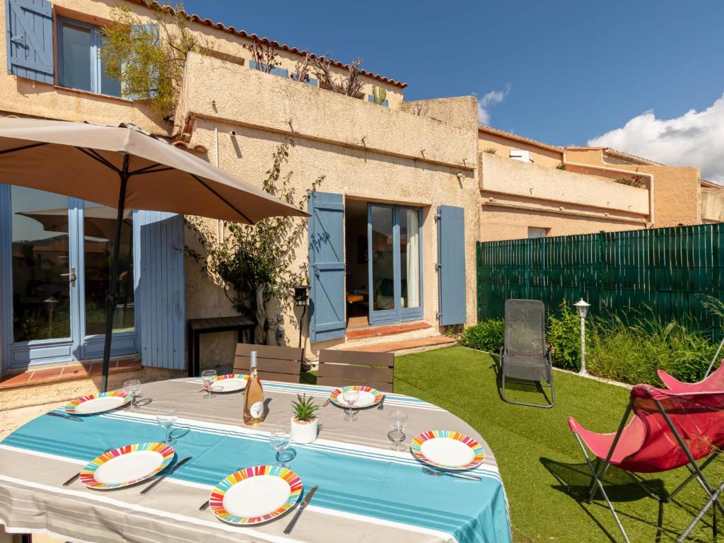 - une table, deux chaises et un parasol dans la cour dans l'établissement Holiday Home Les Jardins d'Hélios-3 by Interhome, à Carqueiranne