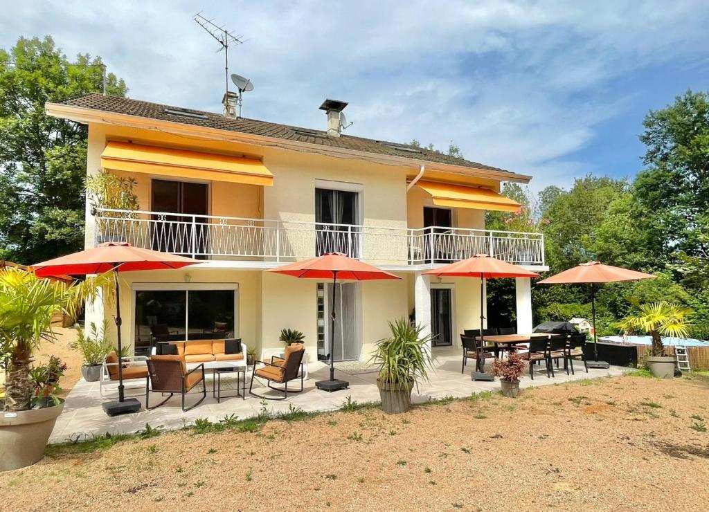 une maison avec des tables, des chaises et des parasols dans l'établissement Charmante Spacieuse, à La Chapelle-de-la-Tour