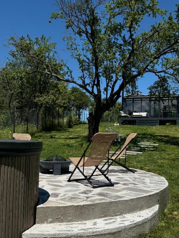 two lawn chairs sitting on a patio under a tree at Crossroads Cabin in Sălişte