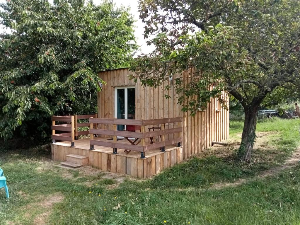 une cabane en bois avec une clôture et un arbre dans l'établissement Gite Nature proche Honfleur, à Fatouville-Grestain