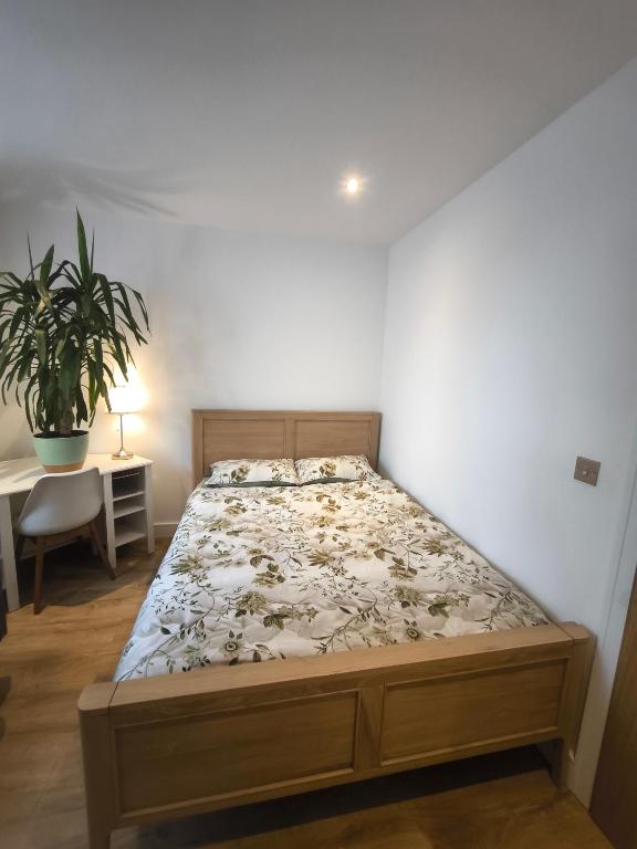 a bed in a room with a plant and a table at Heathrow luxury stay in Feltham