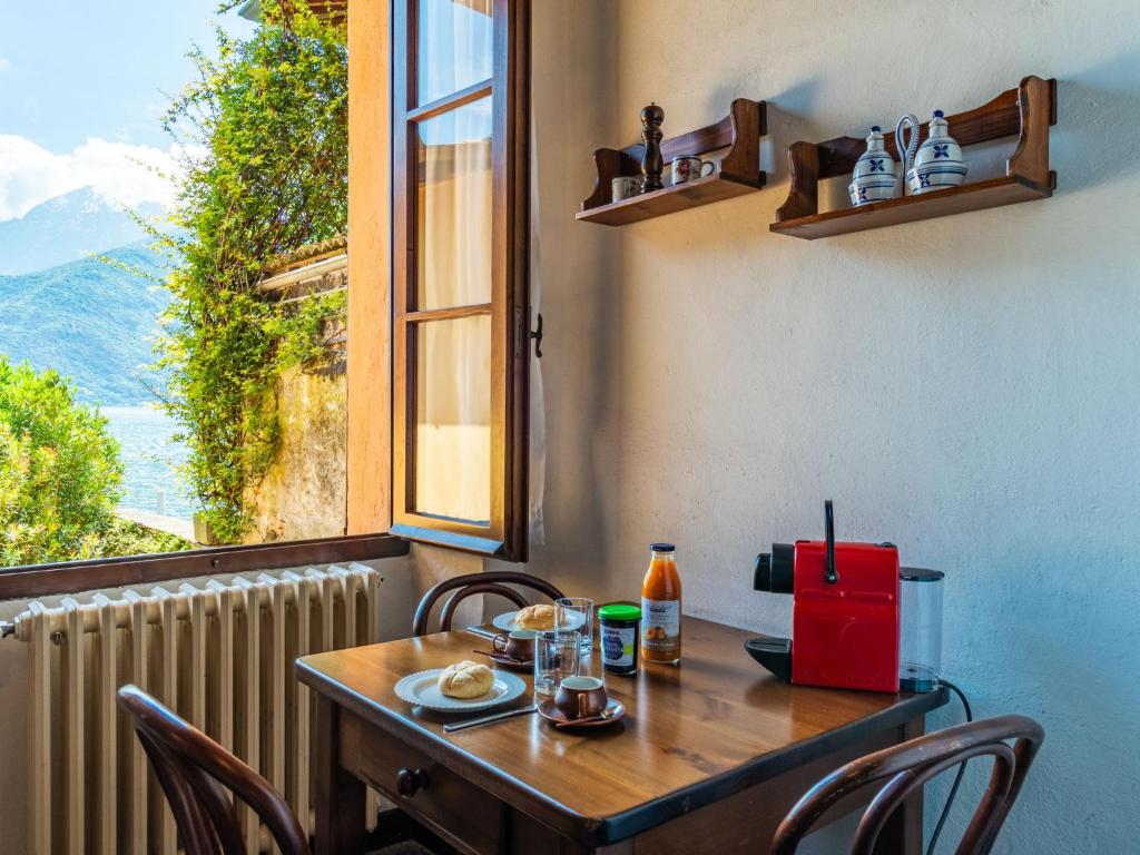 Una mesa con sillas y una ventana y una mesa con comida encima. en Apartment Sissi by Interhome, en Musso