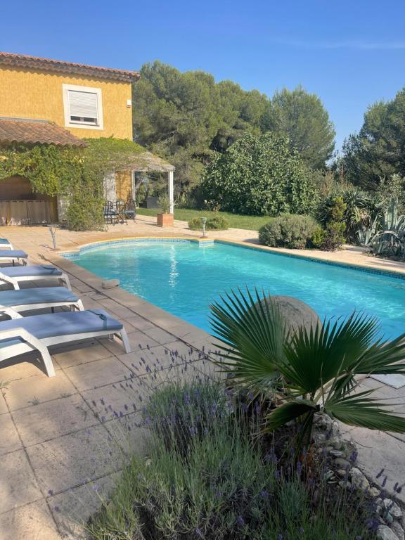 ein Swimmingpool mit Liegestühlen neben einem Haus in der Unterkunft Villa provençale 8 personnes in Ventabren