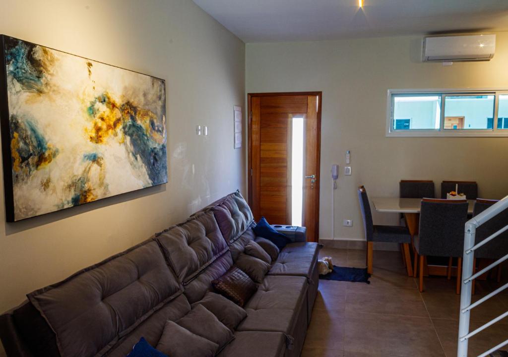 een woonkamer met een bank en een schilderij aan de muur bij Serena Beach Triplex in Caraguatatuba