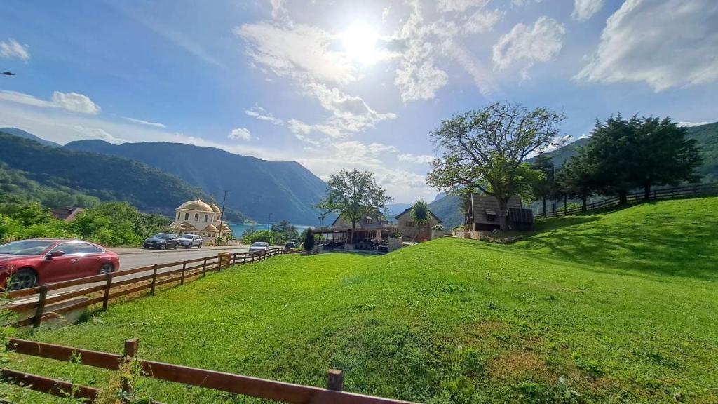 uma colina verde com uma cerca e carros em uma estrada em Apartman Biser Pive em Plužine