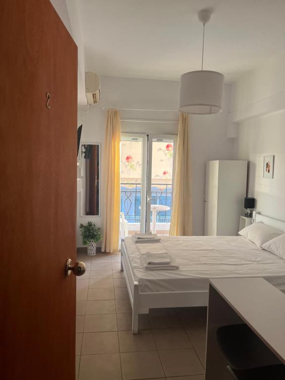 a bedroom with a white bed and a large window at Ermou Studios in Loutra Edipsou