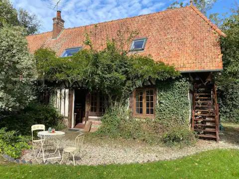 una casa con un tavolo e sedie di fronte di Maison de campagne du XVIIe siècle a Lammerville