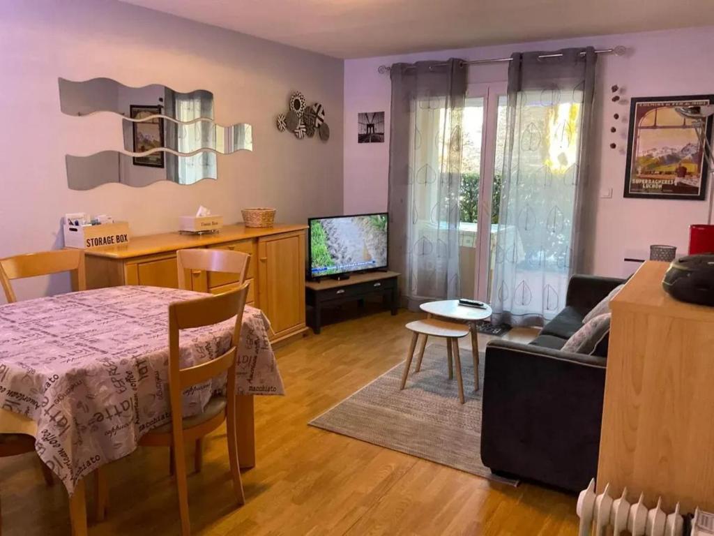 un salon avec une table et une télévision dans l'établissement Appartement moderne à Bagnères-de-Luchon, vue montagne, 53m², à Luchon