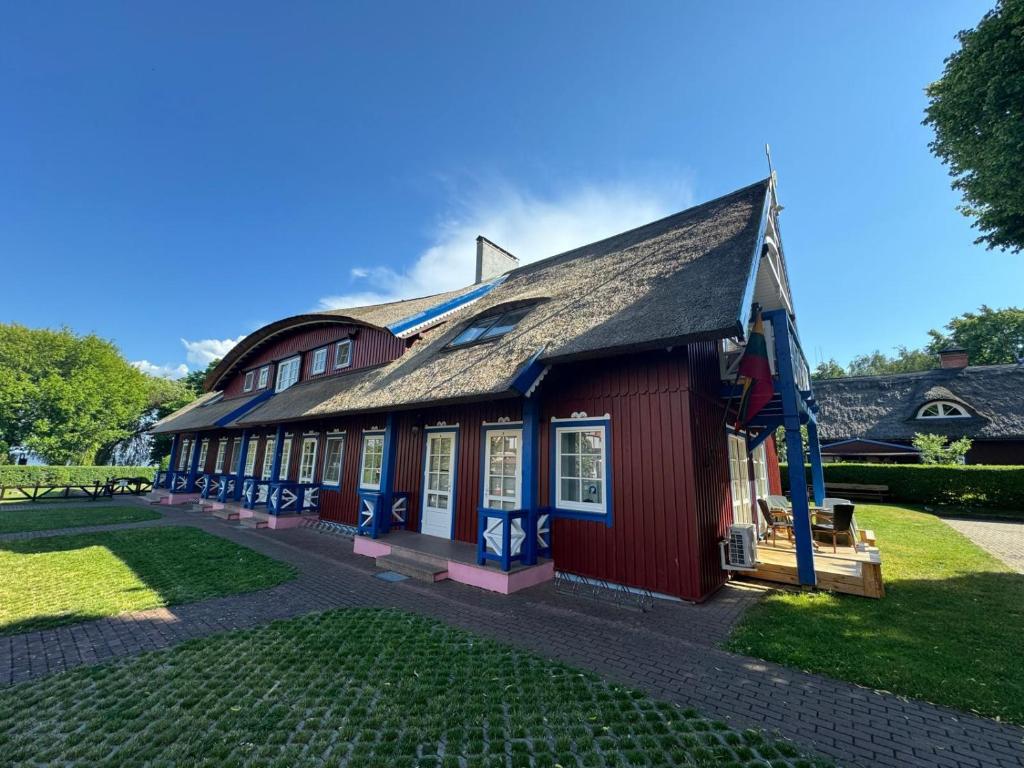 a red building with a gambrel roof at Vila Gija in Nida