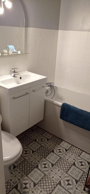 une salle de bain avec un lavabo, une baignoire et des toilettes dans l'établissement F2 en rez de jardin, à Cabourg