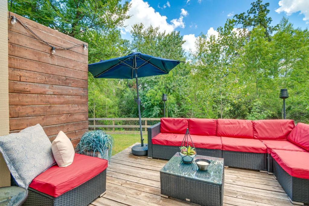 a patio with a red couch and an umbrella at Convenient Bryan Townhome with Patio Less Than 3 Mi to AandM! in Bryan