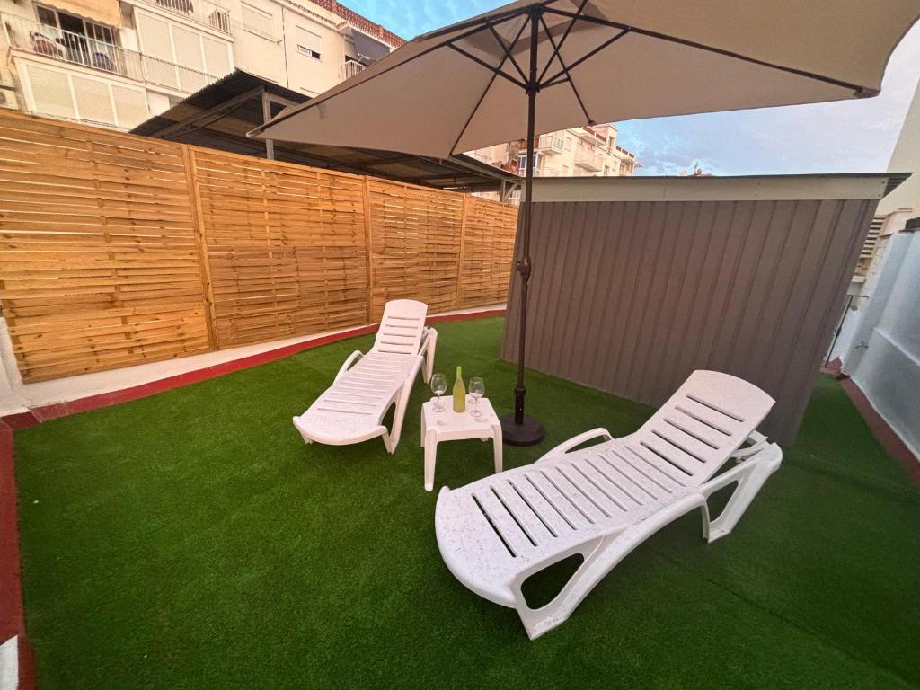 two white chairs and an umbrella on a lawn at Villa Almirante Torrecilla by South Costa in Nerja