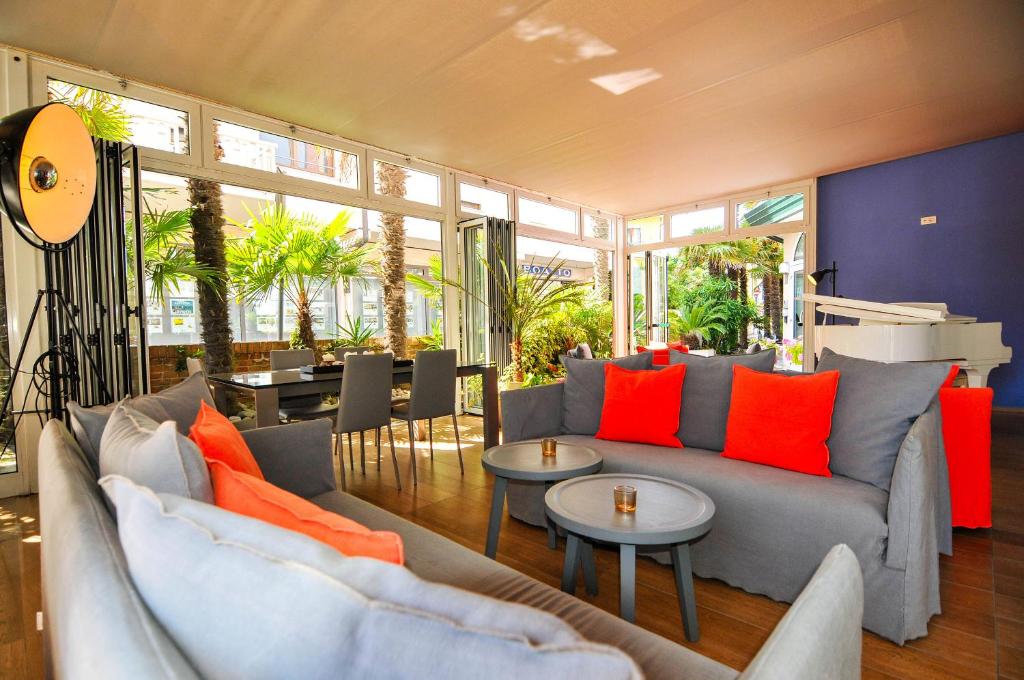 a living room with a gray couch and orange pillows at Eco Hotel Cleofe in Caorle
