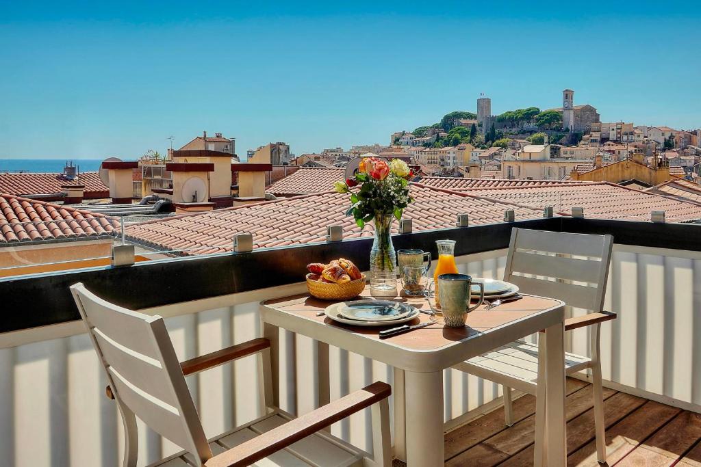 une table avec un vase de fleurs sur un balcon dans l'établissement Downtown Cannes 2BR with AC & Terrace w Sea View - BENAKEY, à Cannes