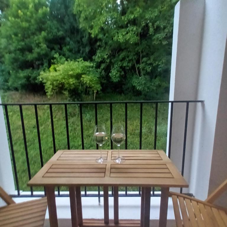 - une table en bois avec 2 verres à vin sur le balcon dans l'établissement Family apartment with parking Metro line 9, à Sèvres