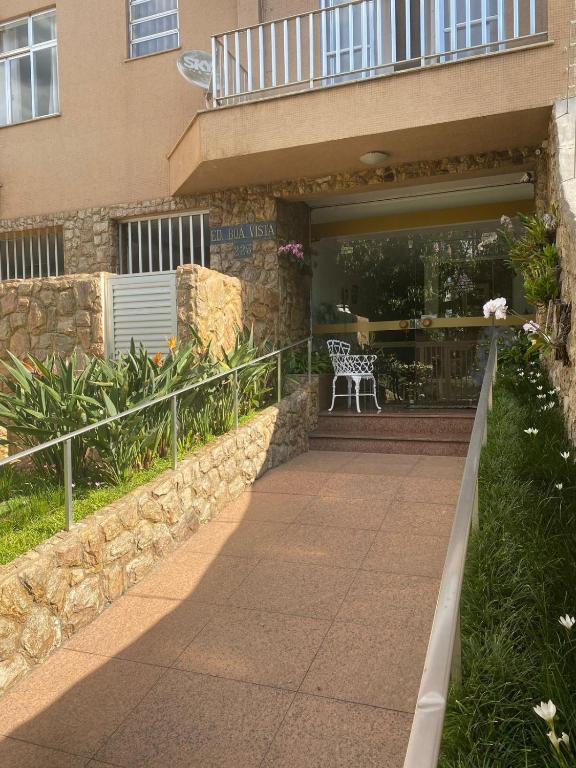 a walkway in front of a building with a bench at Edificio na rua do Parque das Aguas in São Lourenço