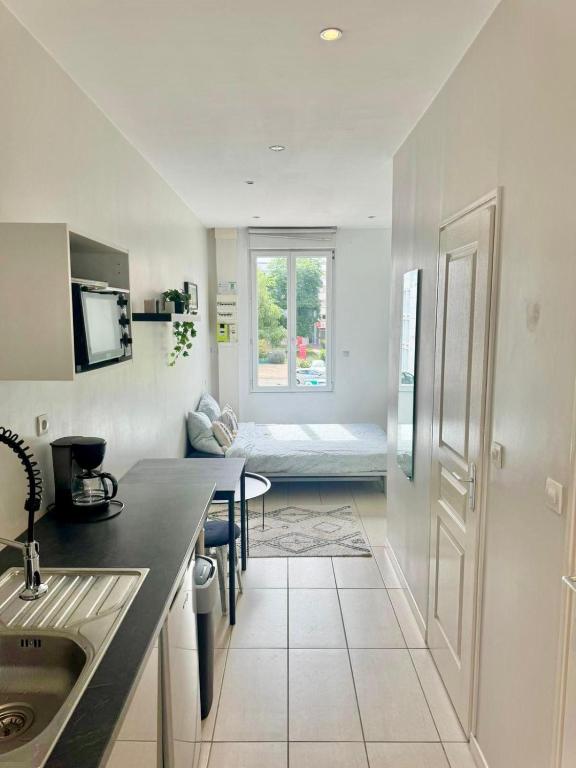 une cuisine avec un évier et une chambre avec un lit dans l'établissement Studio Gabriel, à Villeurbanne