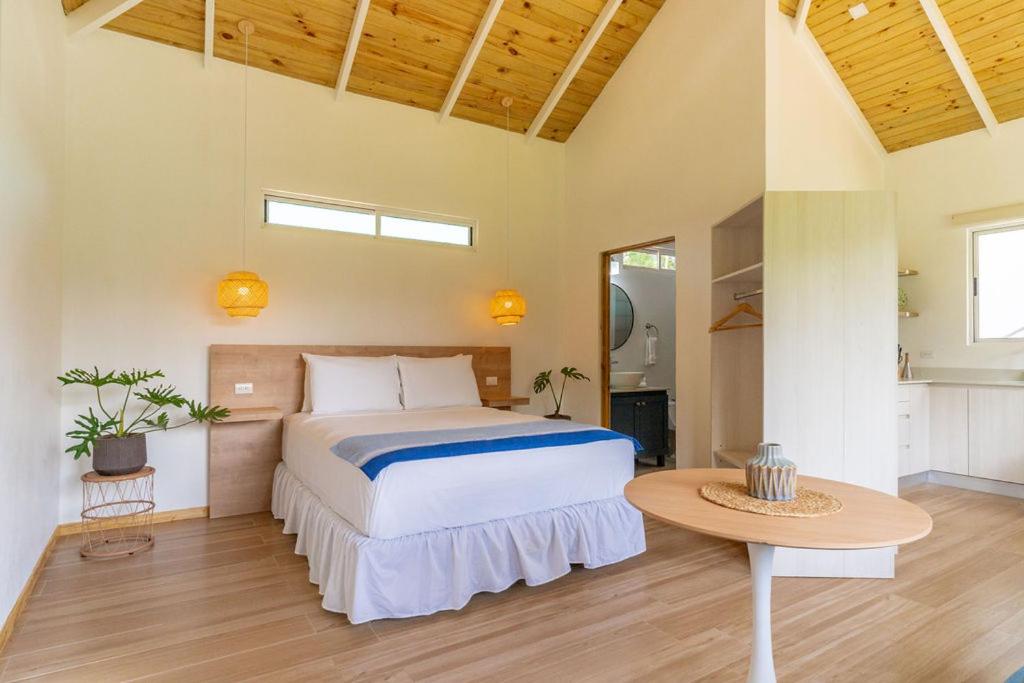 a bedroom with a large bed and a table at Cedrela Beach Villas in Uvita