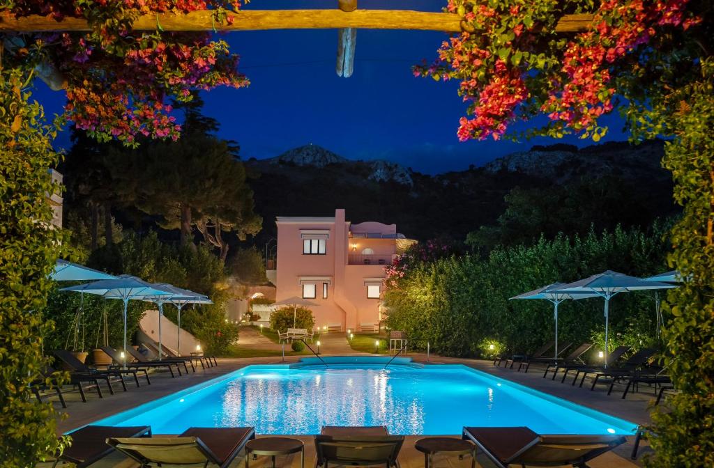 a swimming pool at night with chairs and umbrellas at Boutique Hotel Casa Mariantonia in Anacapri