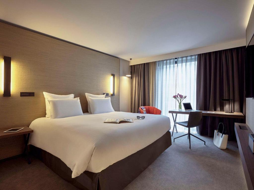a hotel room with a large bed and a desk at Pullman Paris Roissy Cdg Airport in Roissy-en-France