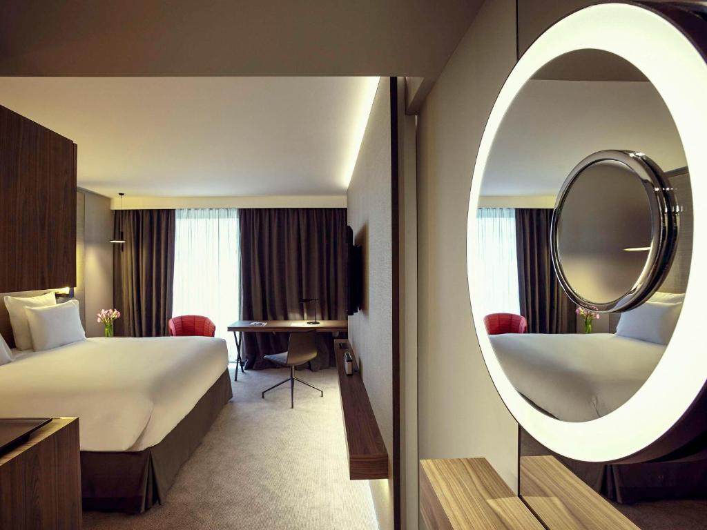 a hotel room with a bed and a mirror at Pullman Paris Roissy Cdg Airport in Roissy-en-France