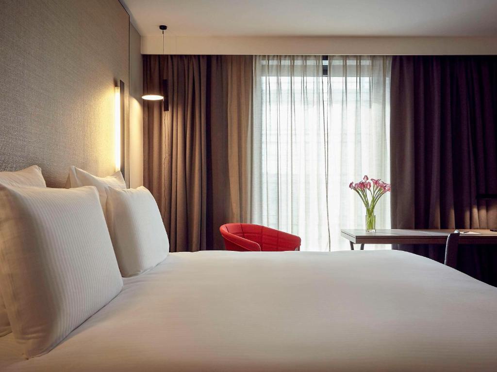 a hotel room with a large white bed and a window at Pullman Paris Roissy Cdg Airport in Roissy-en-France