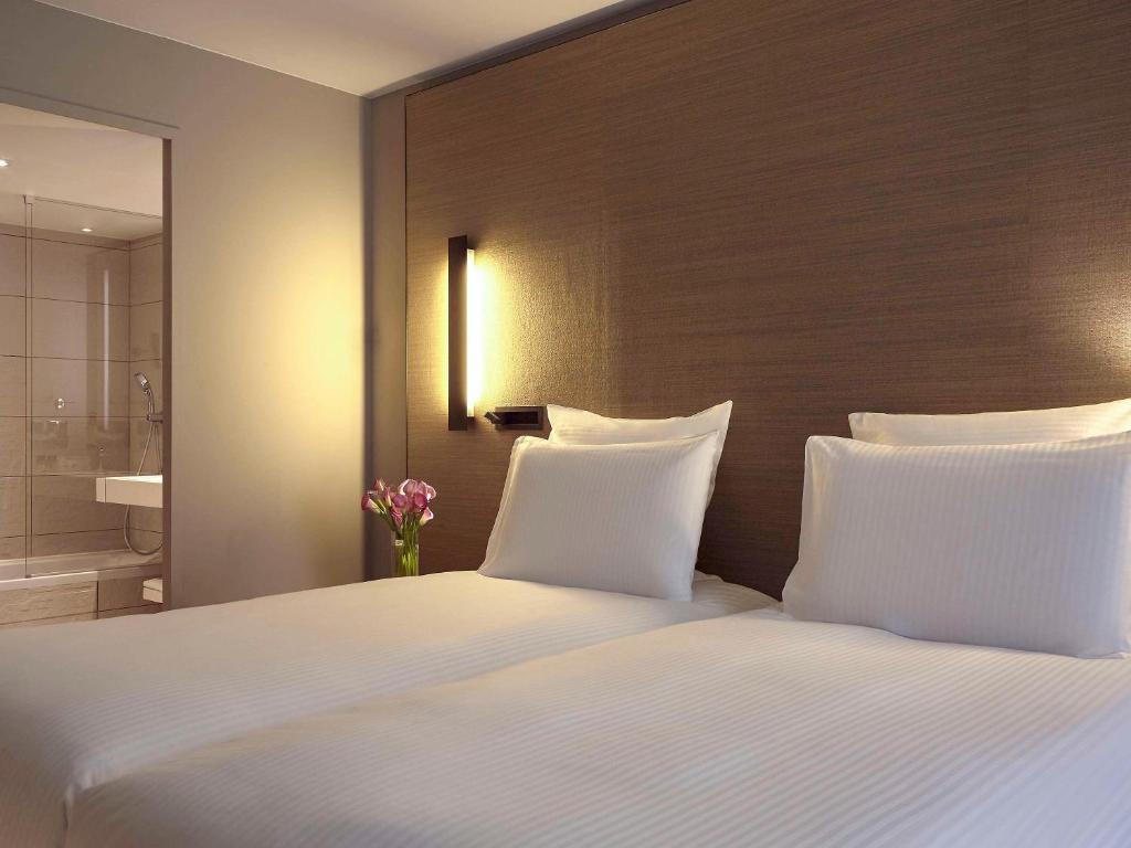 a bedroom with a large bed with white pillows at Pullman Paris Roissy Cdg Airport in Roissy-en-France