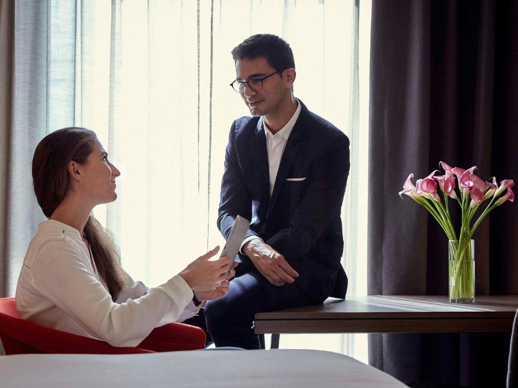 a man and a woman sitting at a table talking at Pullman Paris Roissy Cdg Airport in Roissy-en-France