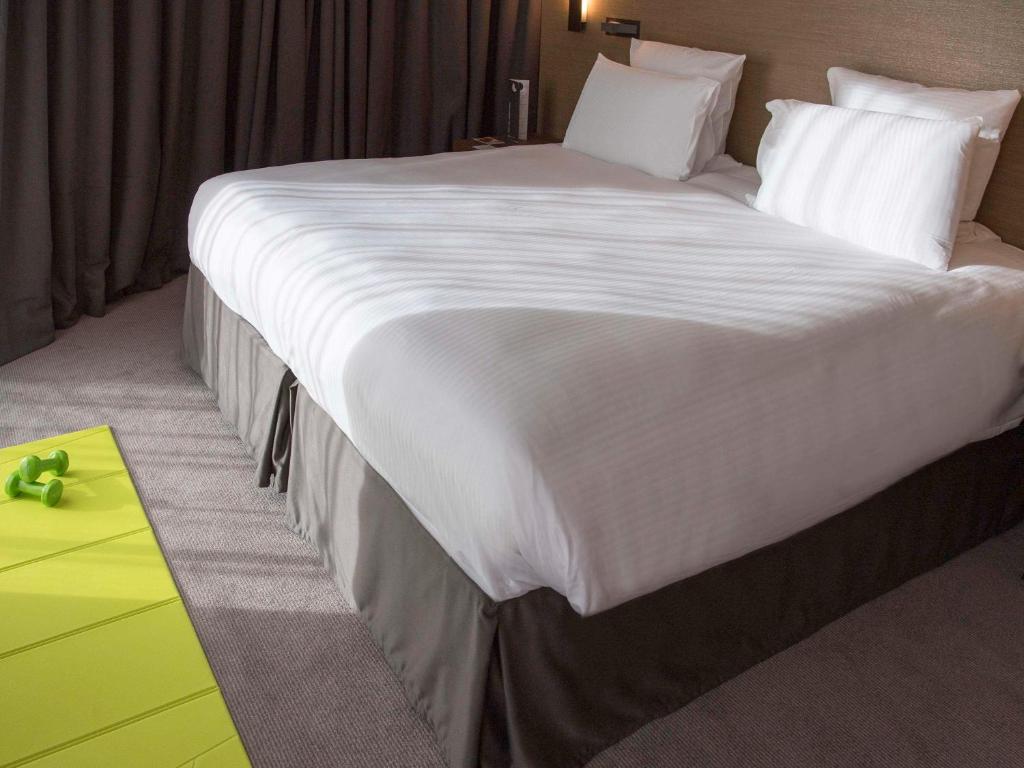 a large white bed in a hotel room at Pullman Paris Roissy Cdg Airport in Roissy-en-France