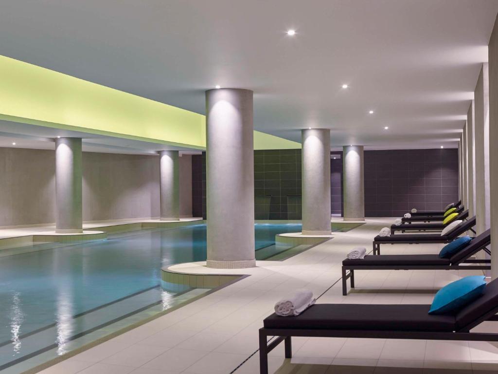 a hotel lobby with a pool and rows of chairs at Pullman Paris Roissy Cdg Airport in Roissy-en-France