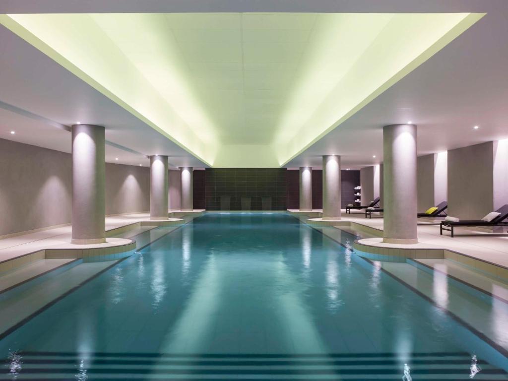 a large swimming pool in a hotel with columns at Pullman Paris Roissy Cdg Airport in Roissy-en-France