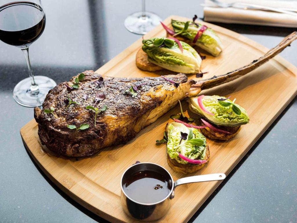 a plate of steak and vegetables and a glass of wine at Pullman Paris Roissy Cdg Airport in Roissy-en-France