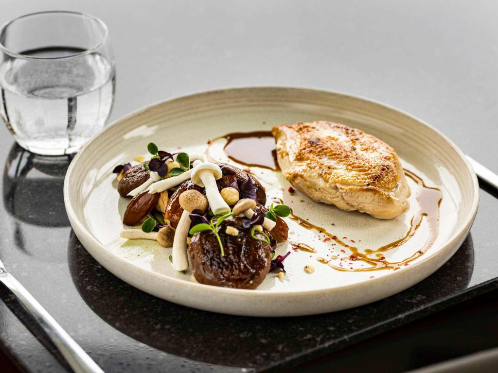 a plate of food on a table with a glass at Pullman Paris Roissy Cdg Airport in Roissy-en-France