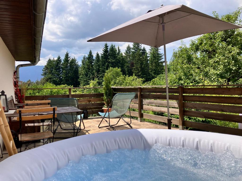 - un bain à remous avec une table et un parasol dans l'établissement Sous le Tilleul Le Studio avec jacuzzi, à Bellegarde-sur-Valserine