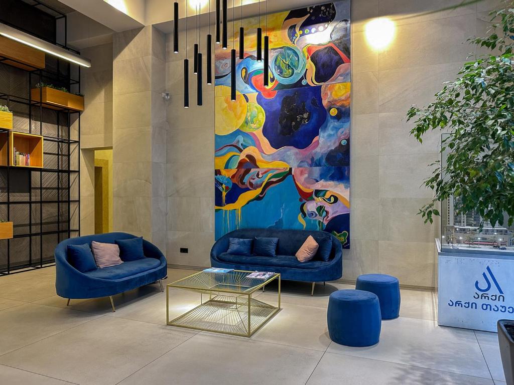 a lobby with two blue chairs and a painting at Downtown Residence in Tbilisi City