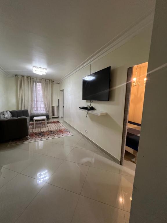 un salon avec un canapé et une télévision au mur dans l'établissement Maisonnette de ville, à Aubervilliers