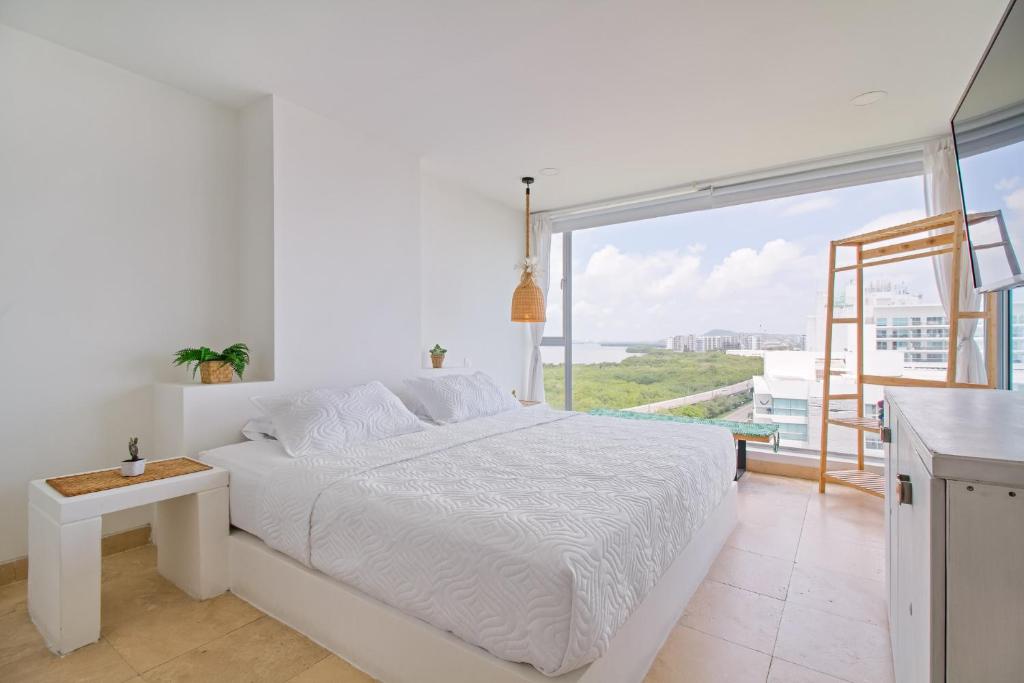 Un dormitorio blanco con una cama y una ventana grande. en Sensacional! Apartamento Cartagena Morros Sonesta, en Cartagena de Indias