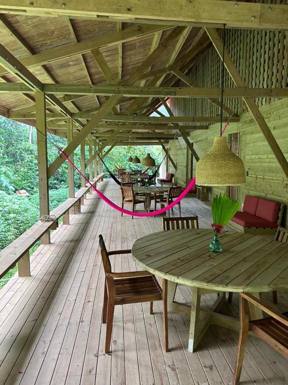 a wooden deck with a wooden table and chairs at Kurrulau Hotel Playa Pacífica in Nabugá