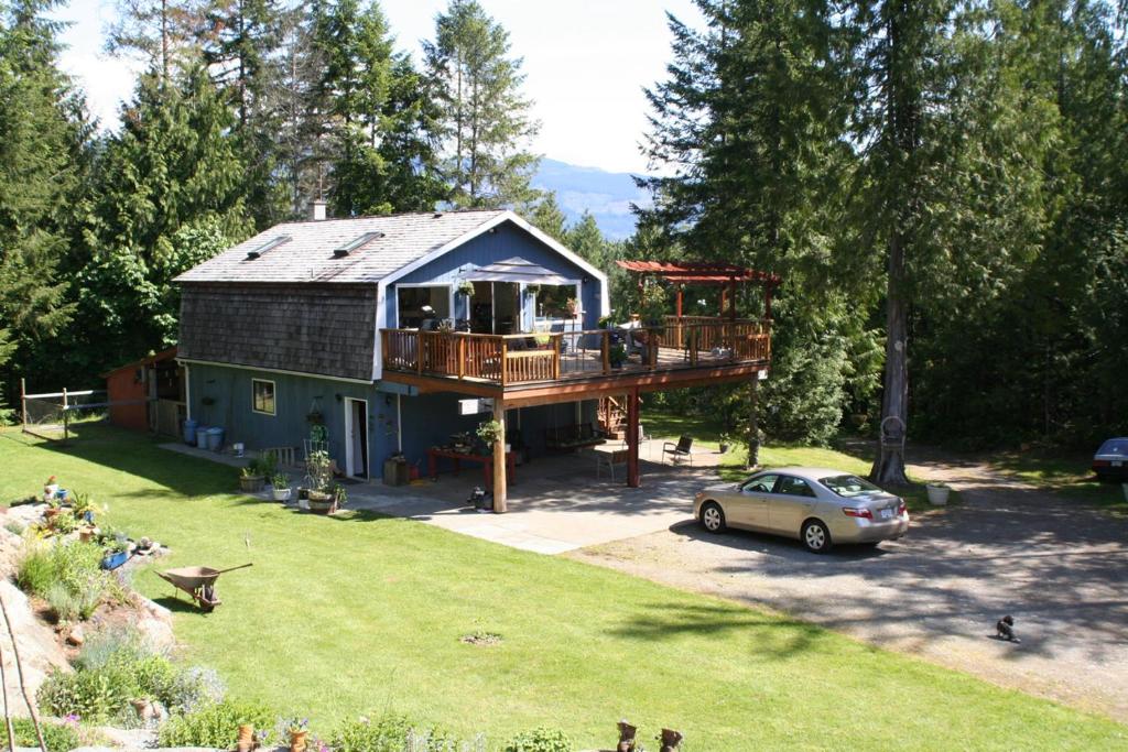 a house with a deck and a car parked in the yard at Beaver Hut Bed And Breakfast in Port Alberni