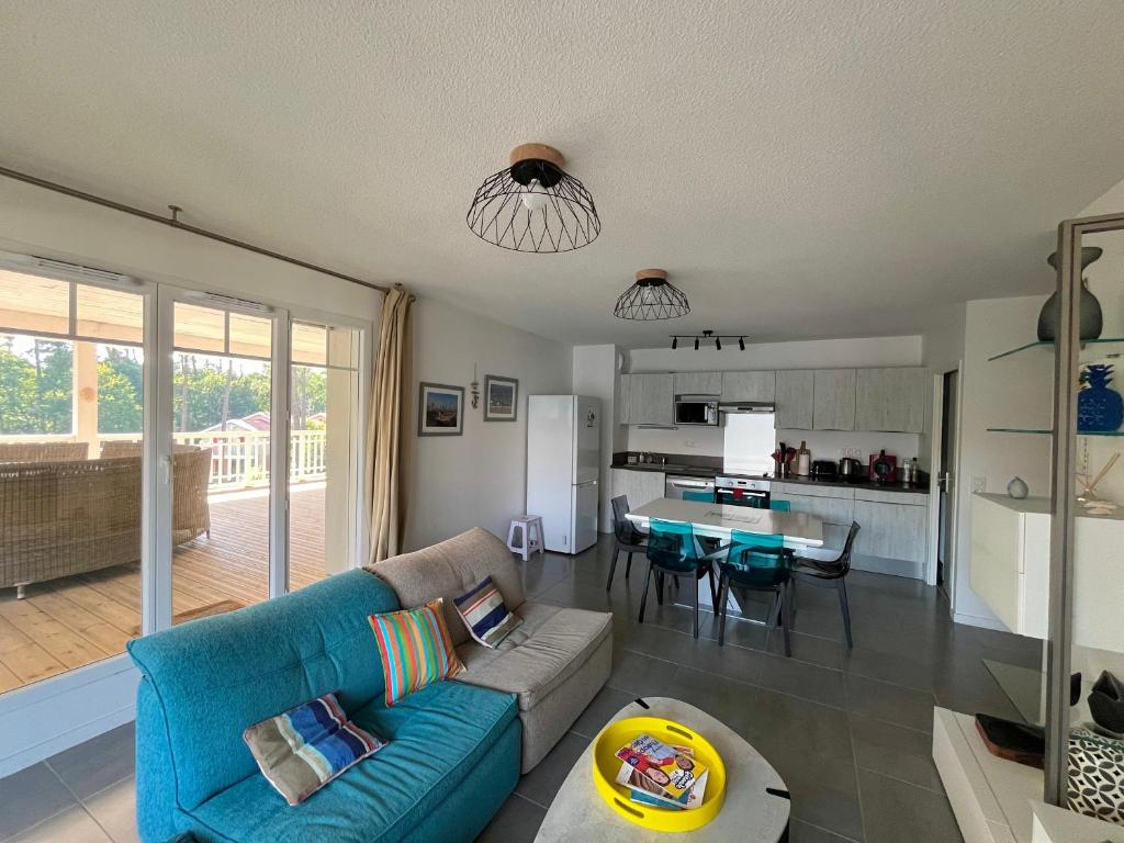 un salon avec un canapé bleu et une cuisine dans l'établissement Appartement T4 avec Terrasse, Piscine et Proche Dune du Pyla - FR-1-319-154, à La Teste-de-Buch