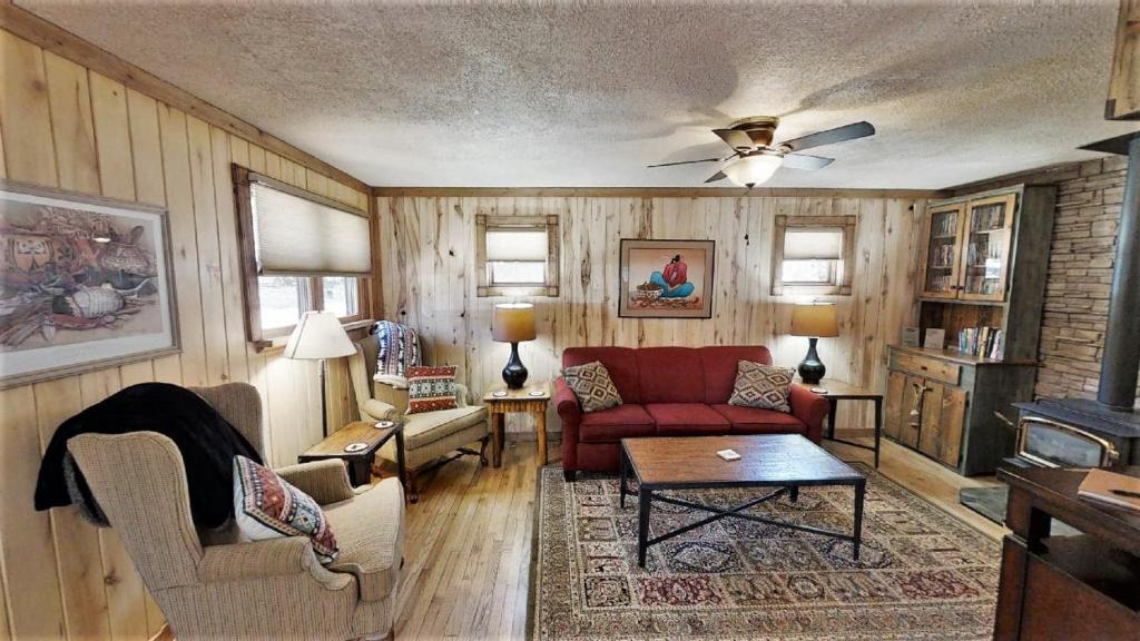 a living room with a red couch and chairs at Knotty & Nice in Red River
