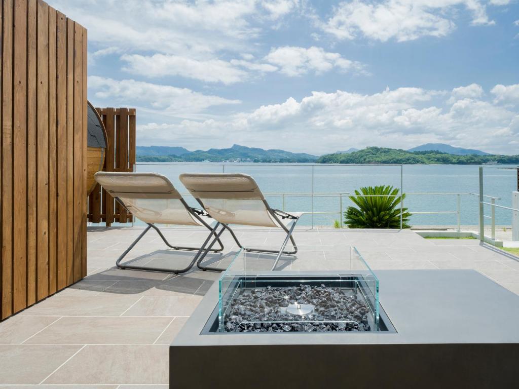 a pair of chairs on a balcony with a view of the water at Rakuten STAY HOUSE Amakusa in Yanagi