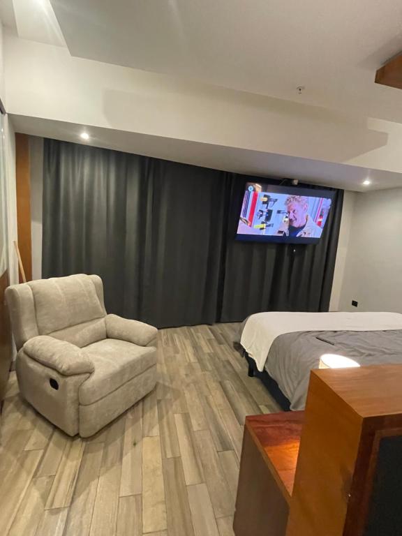 a bedroom with a bed and a chair and a tv at Hotel Sonata Angelopolis in Lomas de Angelopolis