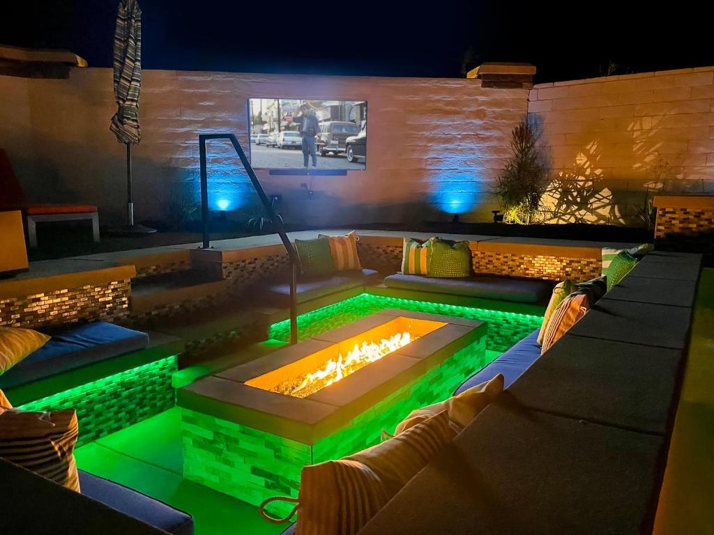インディオにあるThe Desert Social - Firepit, Spa, Pool, Game Roomの緑色のライトが付いたファイヤーピットのあるプール