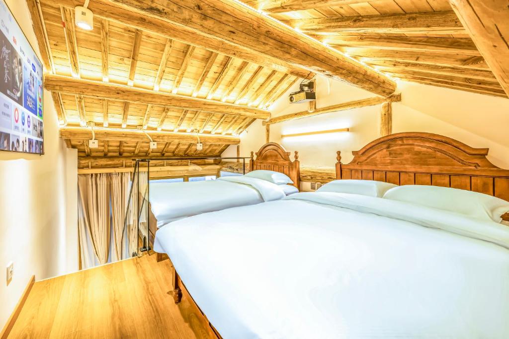 a row of beds in a room with wooden ceilings at The Hutong Courtyard-Very close to Tiananmen Square,Forbidden City,Wangfujing Commercial Street,The hotel has a terrace,Free coffee,Free laundry,Near the subway st ation in Beijing