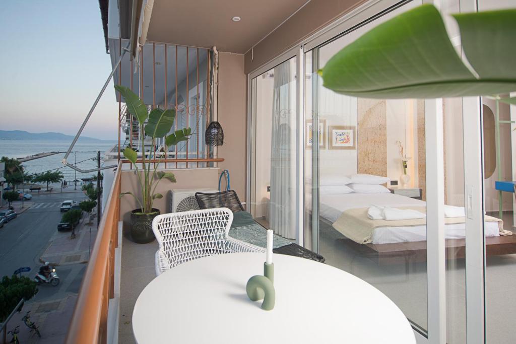 a room with a balcony with a bed and a table at Infinity Blue next to the sea in Kalamata