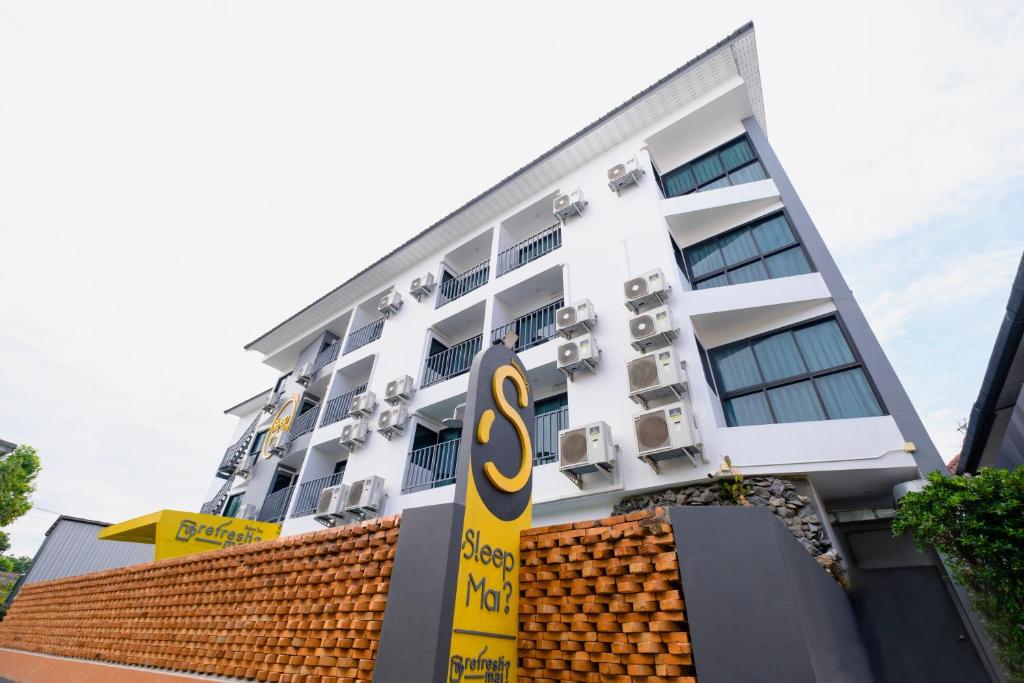 a white building with a s sign in front of it at Sleep Mai Thapae Chiang Mai Old City Lifestyle Hotel in Chiang Mai